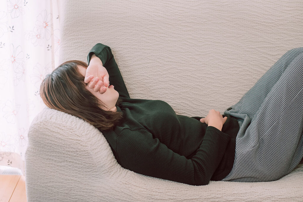 woman laying on couch suffering from period cramps